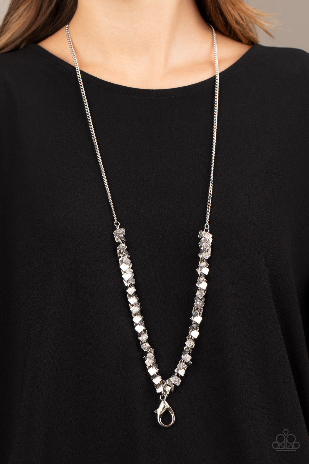 Item #P2LN-SVXX-110XX Delicately hammered in shimmer, dainty silver square frames cluster along the bottom of a classic silver chain, creating a noisy fringe. A lobster clasp hangs from the bottom of the design to allow a name badge or other item to be attached. Features an adjustable clasp closure. Sold as one individual lanyard. Includes one pair of matching earrings.