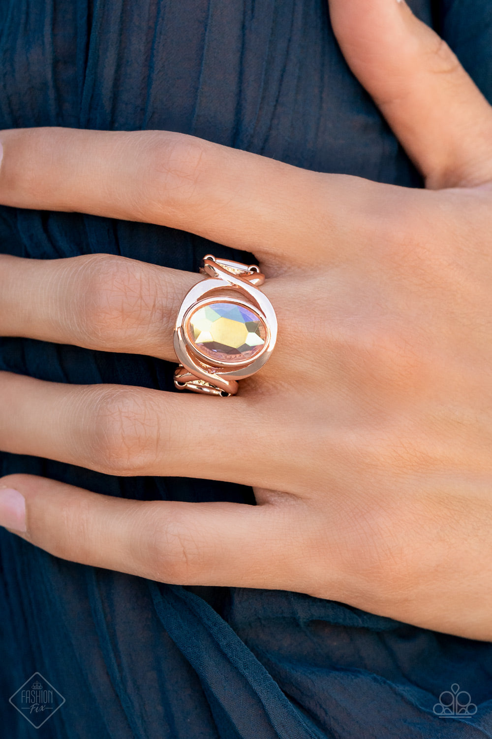 Interwoven rose gold bars delicately encircle an iridescent Pale Rosette gem, creating a mystical centerpiece atop the finger. Features a stretchy band for a flexible fit. Sold as one individual ring.