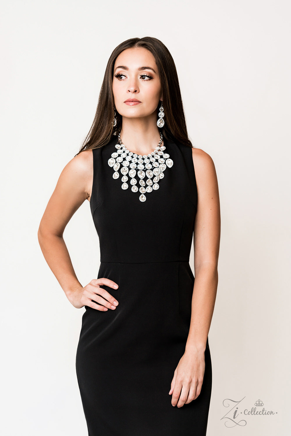 tem #Z916 Encrusted in dainty white rhinestone frames, columns of glassy white gem studded frames increase in size as they drip below the collar. Varying in size and number, white rhinestone encrusted teardrop gems link together as they trickle down the chest , creating a plunging fringe for a ,mesmerizing finish. Features an adjustable clasp closure. Sold as one individual necklace. Includes one pair of matching earrings.