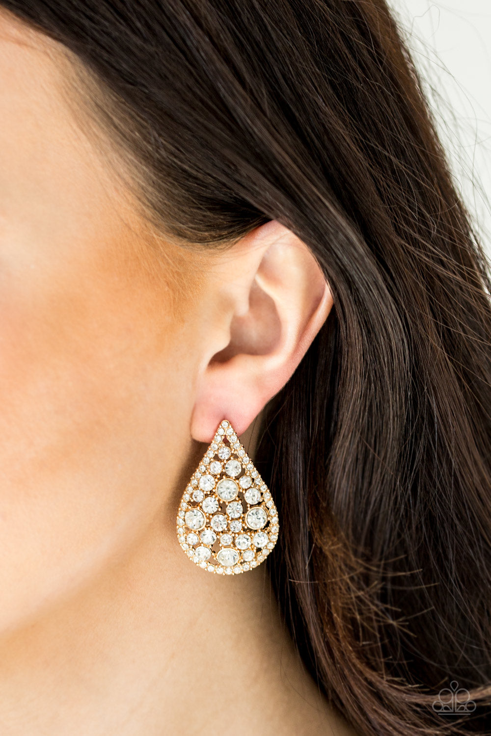Radiating with glassy white rhinestones, oversized gold teardrops adorn the ear for a dramatic flair. Earring attaches to a standard post fitting. Sold as one pair of post earrings.