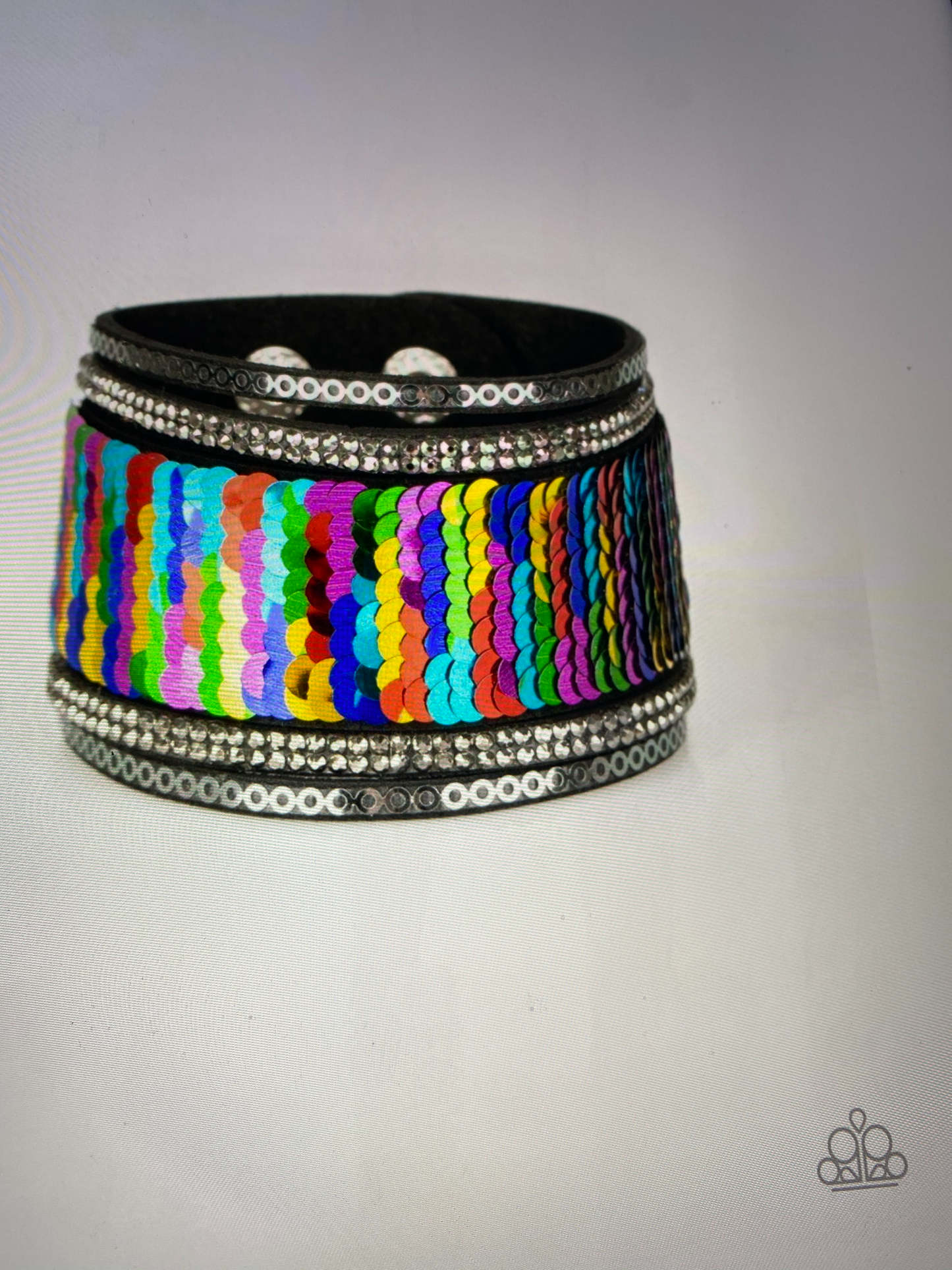 Infused with strands of smoky hematite rhinestones and dainty metallic accents, row after row of shimmery sequins are stitched across the front of a spliced black suede band. Bracelet features reversible sequins that change from multicolored to silver. Features an adjustable snap closure.  Sold as one individual bracelet.